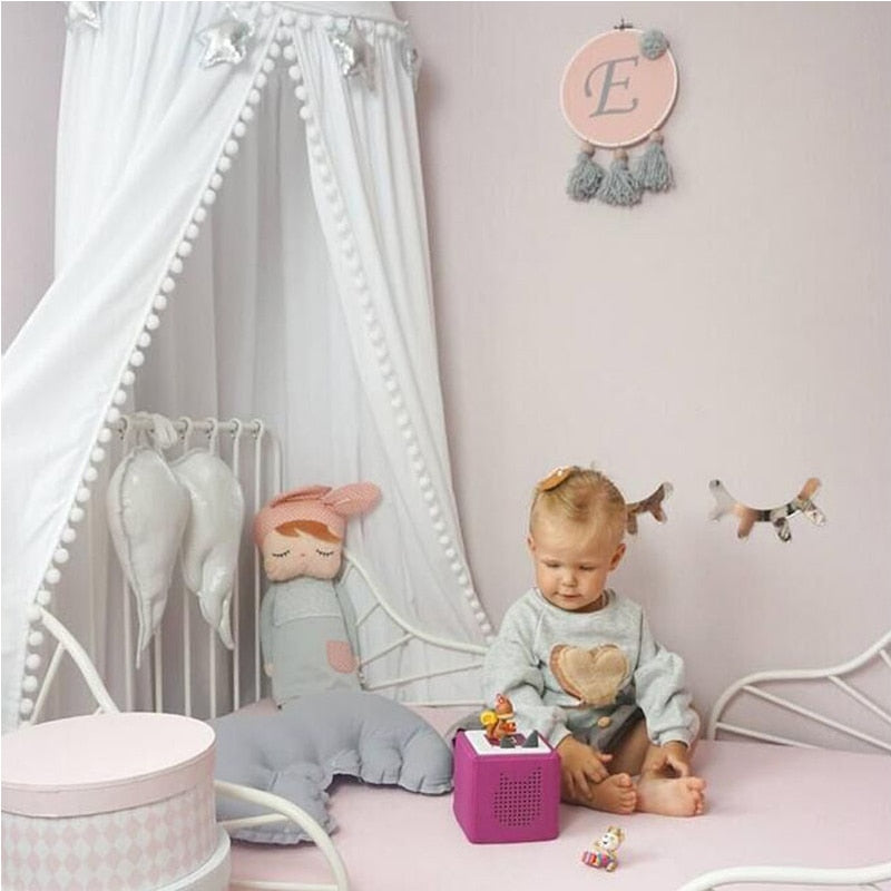 Kinderzimmer-Dekoration mit Pompon-Baldachin und Moskitonetz